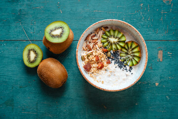 Healthy breakfast, oatmeal, kiwi and granola on green background