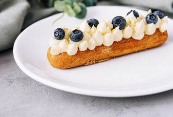 Tasty French eclairs with cream and fresh berries
