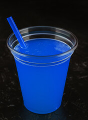 blue juice into glass over black background
