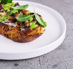 Toast with fried porcini mushrooms on white plate