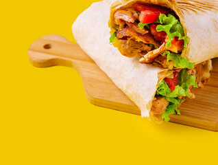 shawarma with chicken, tomatoes and lettuce on a wooden board
