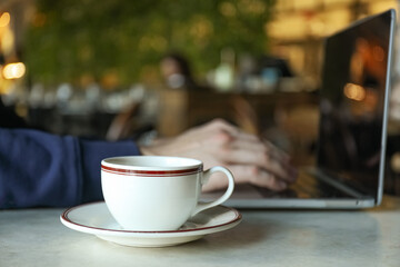 A cup of coffee on a table near a laptop in a cafe