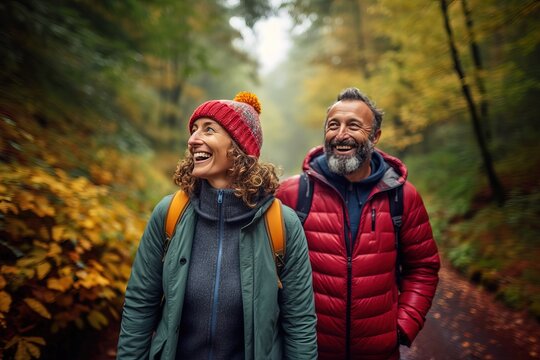 A photorealistic image of a couple of middle-aged hikers walking through an autumn forest in rainy weather. They happily communicate during their walk.