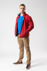 Fototapeta premium A man of athletic build in a red jacket stands and holds his hands in his pockets