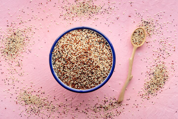 Quinoa mix. Mixed white, red and black quinoa seeds in a bowl, overhead flat lay shot on a pink background