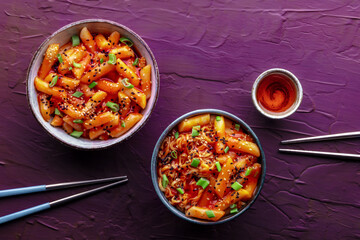 Tteokbokki or topokki and rabokki, Korean street food, spicy rice cakes in red pepper gochujang sauce, overhead flat lay shot with a drink and chopsticks
