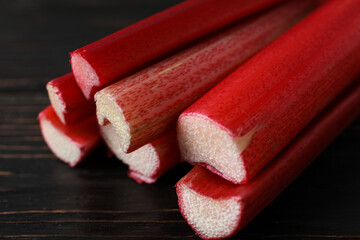 Stalk of rhubarb on dark wooden background, close up