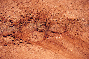 Footprint of leg in sports shoes on sand on open air sport court. Textured background. Concept of sport, hobby, active lifestyle, health, endurance and strength, ad