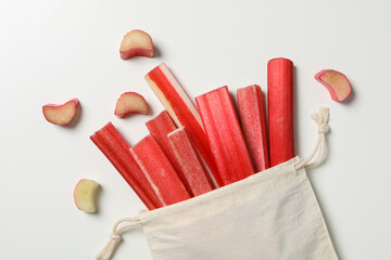 Rhubarb stalk in cotton bag, with pieces around, on white background, top view, close-up