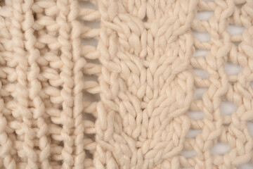 A fragment of beige knitted fabric, knitted from white sheep wool.