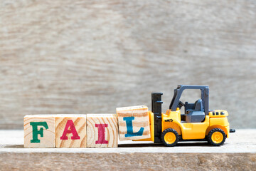 Toy forklift hold letter block l to complete word fail on wood background