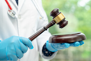 Doctor holding judge gavel, forensic medicine, medical law and crime justice concept. - obrazy, fototapety, plakaty