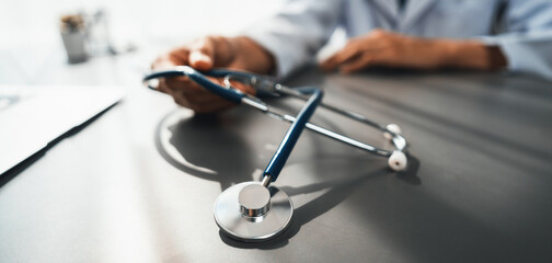 Focus stethoscope on doctor office with blurred background of doctor reviewing medical report and...