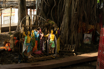 Naklejka premium abandoned hindu religious idols kept isolated, illuminated by narrow sun ray through the foliage of a big tree