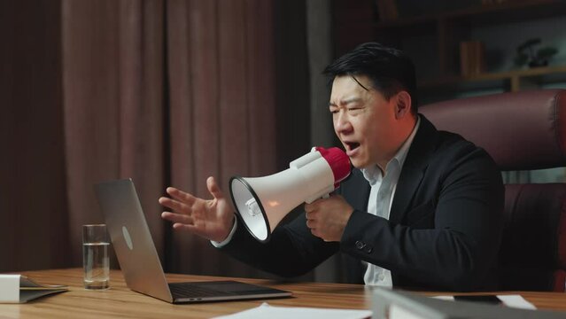 Side view of executive feeling pissed off and yelling in loudspeaker during video conference on portable device. Asian director taking disciplinary action with lazy employees for insufficient work.