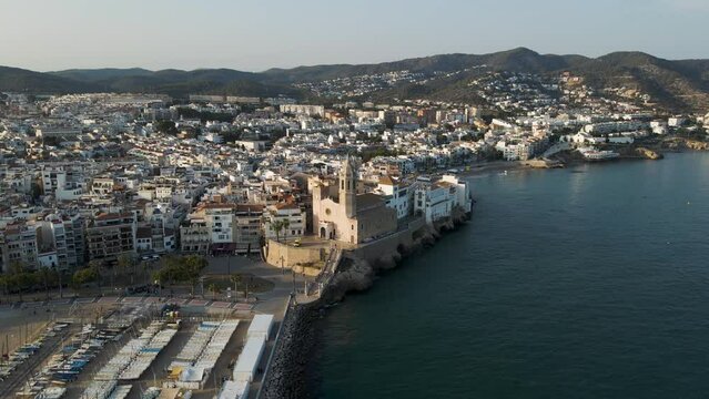 Aerial view of Sitges harbour and skyline along the Mediterranean Sea at sunset, Barcelona, Spain.