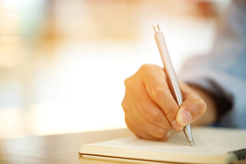 close up hand young man are sitting using pen writing Record Lecture note pad into the book on the...