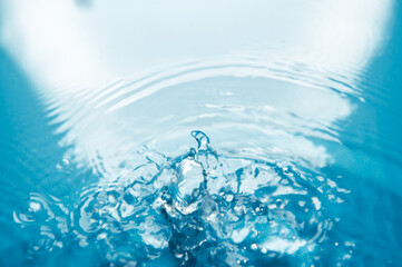 Defocus blurred blue color water ripple surface clear calm texture background with splashing bubbles water drop. Abstract and nature concept. Shiny water wave sunlight reflection shining copy space.