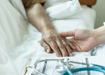 Elderly senior aged patient on bed with geriatric doctor holding hands for trust and nursing health...
