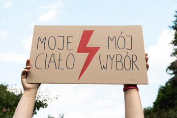 Female protester with placard sign supporting abortion rights in Poland. Women's Strike protest rally demonstration after death of young pregnant woman. Moje ciało, mój wybór is My body, my choice. - obrazy, fototapety, plakaty