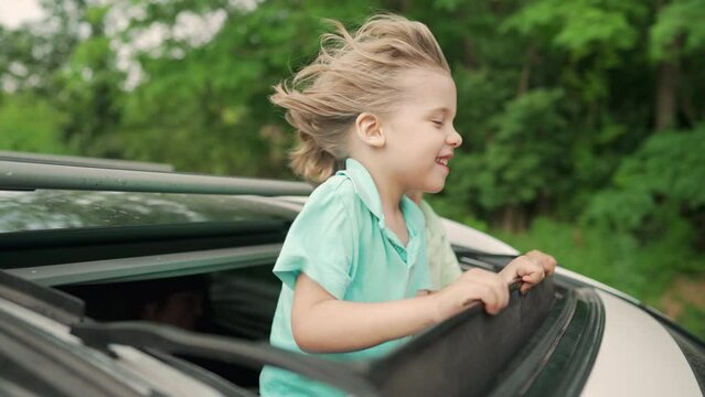 Adorable happy little boys children in open car sunroof during road trip, summer