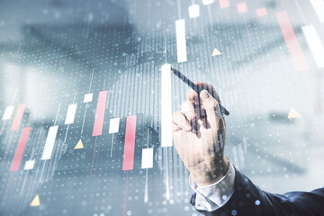 Multi exposure of businessman hand with pen working with virtual creative financial graph and world map on blurred office background, forex and investment concept
