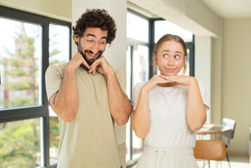 young adult couple feeling thoughtful, wondering or imagining ideas, daydreaming and looking up to copy space