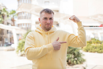 Fototapeta premium handsome man feeling happy, satisfied and powerful, flexing fit and muscular biceps, looking strong after the gym