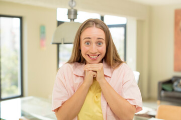pretty blond woman happy and excited, surprised and amazed, giggling with a cute expression