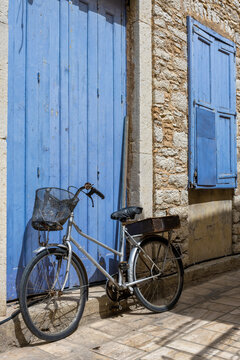 Bicycle Lying Against Blue Door in Greece