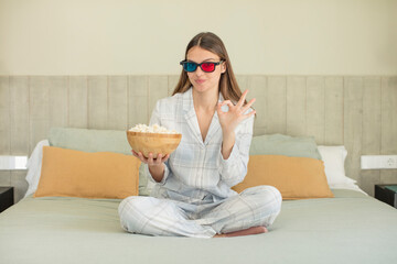 Obraz premium young pretty woman feeling happy, showing approval with okay gesture. popcorns and movie concept