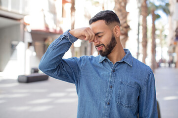 young handsome man feeling disgusted, holding nose to avoid smelling a foul and unpleasant stench