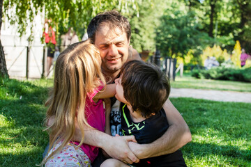 Fototapeta na wymiar happy dad hugs children girl and boy in nature. Family holiday