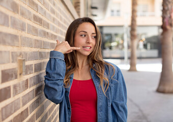 pretty woman smiling cheerfully and pointing to camera while making a call you later gesture, talking on phone