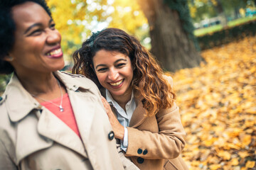 Happy woman friends walking in the forest in autumn. They are chatting and having fun.