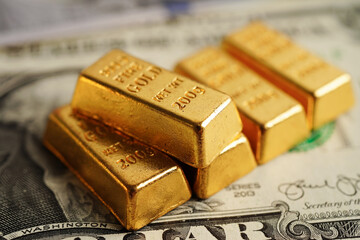 Gold bars on US dollar banknote money, finance trading investment business currency concept.