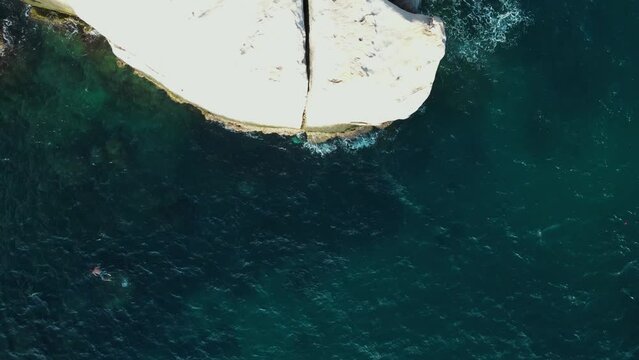 Aerial view of person standing on granite boulder and jumping into sea at Tanote bay, Ko Tao, Thailand.
