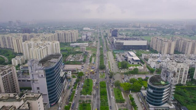 aerial drone shot flying between buildings with cityscape skyscrapers roads on cloudy monsson day with distant buildings lost in fog and green feilds
