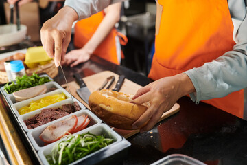 Closeup image of food truck worker putting pork floss in cut wheat bun
