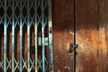Old gold steel lock and damaged and rusted steel door on wooden door. Locked on wooden door with...