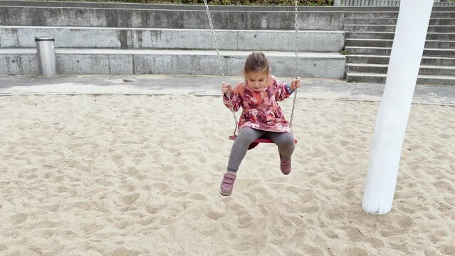 Child girl swing on the playground, kids development 