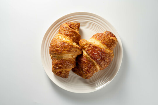 Fresh croissants in a plate isolated, over white background, top view.