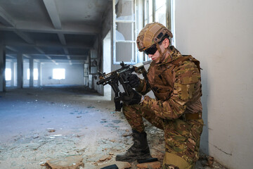 Soldier in action near window changing magazine and take cover