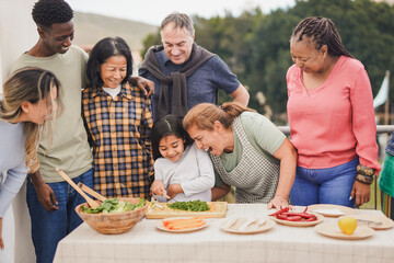 Multi generational people cooking at house rooftop - Multiracial friends preparing food with female child outdoor during weekend day - Grandmother having fun with granddaughter