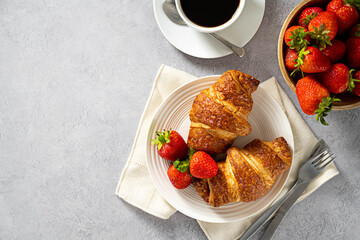 Fresh croissants for breakfast, with coffee and fresh strawberries. Copy space