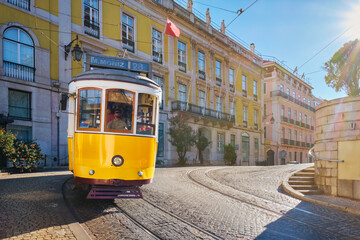 Famous vintage yellow tram 28 in the narrow streets of Alfama district in Lisbon, Portugal - symbol of Lisbon, famous popular travel destination and tourist attraction - obrazy, fototapety, plakaty