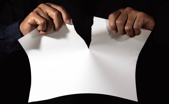 Male hand tearing paper close up on a dark background - Powered by Adobe