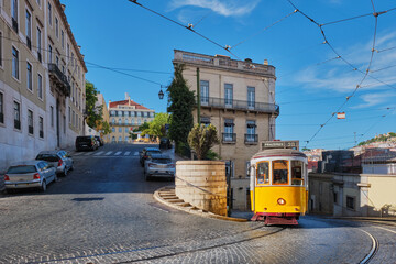 Famous vintage yellow tram 28 in the narrow streets of Alfama district in Lisbon, Portugal - symbol of Lisbon, famous popular travel destination and tourist attraction - 621964409