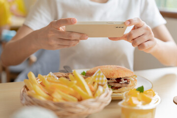 restaurant owner takes a picture of the food on the table with a smartphone to post on a website. Online food delivery, ordering service, influencer, review, social media, share, marketing, interest.