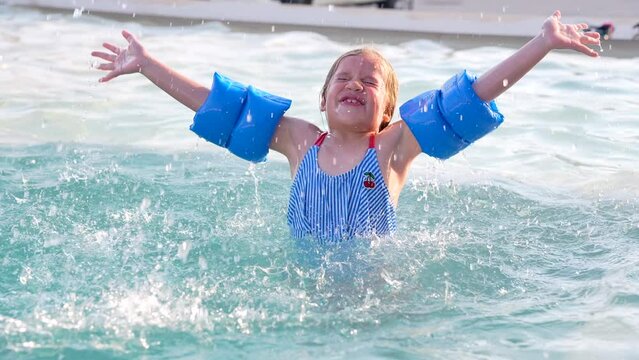 Niña rubia latina hispana muy contenta y feliz nadando en la piscina en la alberca al aire libre una tarde de un día soleado disfrutando y divertida flotando y saltando en el agua en el verano
